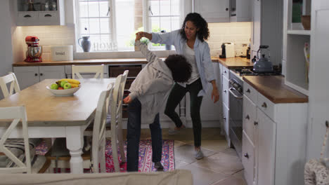 Mixed-race-lesbian-couple-and-daughter-dancing-in-kitchen