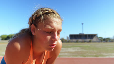 Front-view-of-Caucasian-female-athlete-taking-a-break-on-a-sports-track-4k