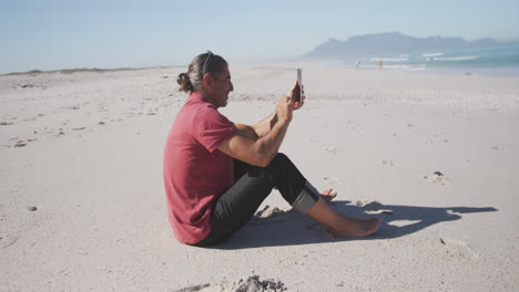Senior-Caucasian-man-using-a-digital-tablet-on-the-beach