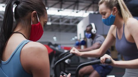 Female-fitness-trainer-and-client-wearing-face-masks-at-gym