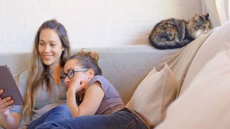 Lesbian-couple-using-digital-tablet-in-living-room-4k