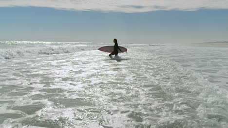 Mujer-Con-Tabla-De-Surf-Corriendo-En-El-Mar-4k