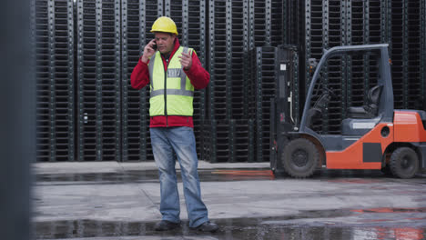 Warehouse-worker-talking-on-phone-outside-factory