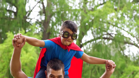 Pow-text-on-speech-bubble-against-dad-carrying-his-son-in-superhero-costume