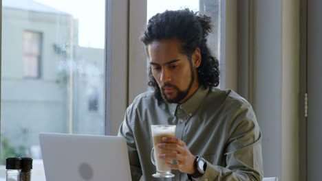 Executive-having-coffee-while-using-laptop-4k