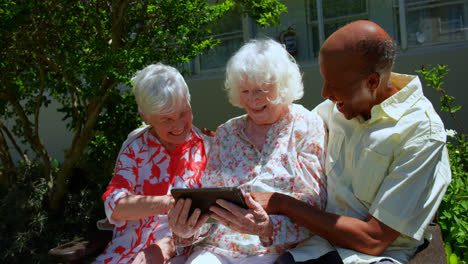 Gruppe-Aktiver-Seniorenfreunde-Gemischter-Herkunft,-Die-Im-Garten-Eines-Pflegeheims-Ein-Digitales-Tablet-Verwenden-4k
