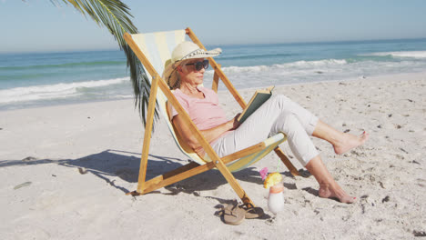 Senior-Caucasian-woman-sitting-on-sunbeds-at-the-beach.