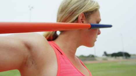 Close-up-of-Caucasian-female-athlete-practicing-javelin-throw-at-sports-venue-4k