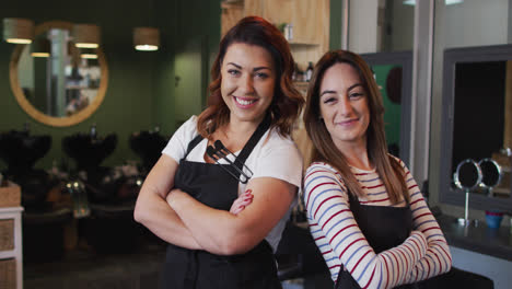 Portrait-of-two-Female-hairdressers-smiling-at-hair-salon