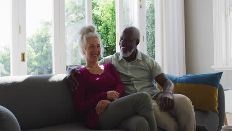 Porträt-Eines-älteren-Paares-Gemischter-Abstammung,-Das-Lächelt,-Während-Es-Zu-Hause-Auf-Der-Couch-Sitzt
