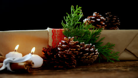 Burning-candles,-gift-box-and-pine-cones-against-black-background-4k