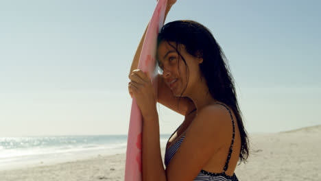 Female-surfer-leaning-on-the-surfboard-on-beach-4K-4k