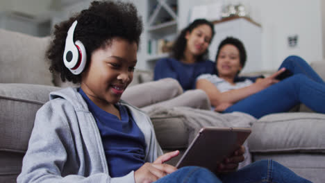 Mixed-race-girl-using-a-digital-tablet-with-headphones-on