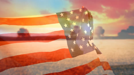 Man-holding-American-flag-against-sunset