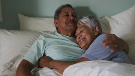 Älteres-Gemischtrassiges-Paar-Umarmt-Und-Lächelt-Im-Bett-Liegend