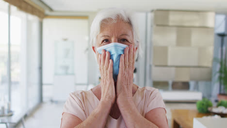 Portrait-of-senior-caucasian-woman-wearing-face-mask-at-home