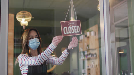 Female-hairdresser-wearing-face-mask-changing-sign-board-Closed-to-Open-at-hair-salon