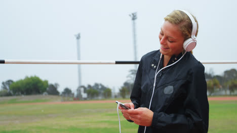 Front-view-of-Caucasian-female-athlete-listening-music-on-mobile-phone-at-sports-venue-4k