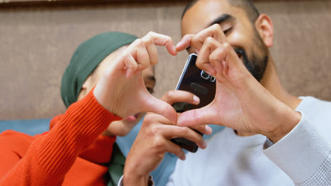 Couple-forming-heart-shape-sign-while-taking-photo-with-mobile-phone-4k