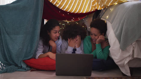 Mixed-race-lesbian-couple-and-daughter-using-tablet-lying-in-bedroom-camp