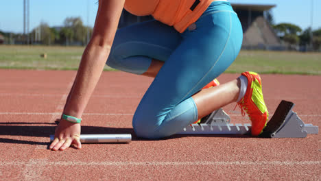 Side-view-of-female-athlete-taking-starting-position-on-a-running-track-4k