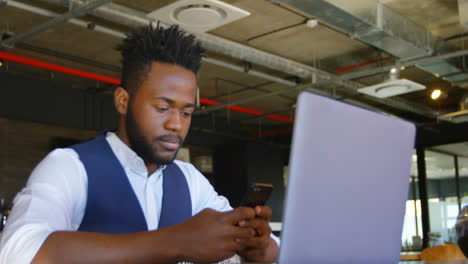 Front-view-of-young-black-businessman-working-on-mobile-phone-in-a-modern-office-4k