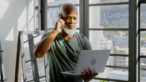 Senior-man-talking-on-mobile-phone-while-using-laptop-4k