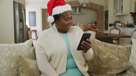 Happy-senior-african-american-woman-wearing-santa-hat-at-chrsitmas-time