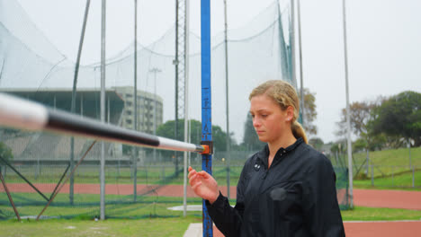 Front-view-of-Caucasian-female-athlete-checking-high-jump-bar-at-sports-venue-4k