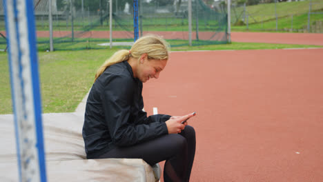 Seitenansicht-Einer-Kaukasischen-Sportlerin,-Die-Ihr-Mobiltelefon-Am-Sportort-Nutzt,-4K