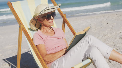 Senior-Caucasian-woman-sitting-on-sunbeds-at-the-beach.