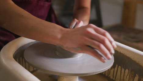 Close-up-view-of-female-potter-creating-pottery-on-potters-wheel-at-pottery-studio