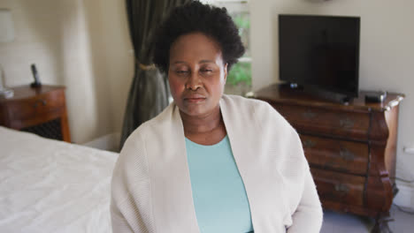 Nachdenkliche-Afroamerikanische-ältere-Frau,-Die-Zu-Hause-Auf-Dem-Bett-Sitzt
