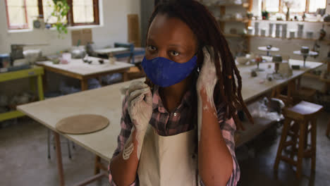 Portrait-of-female-african-american-potter-with-dirty-hands-in-clay-at-pottery-studio