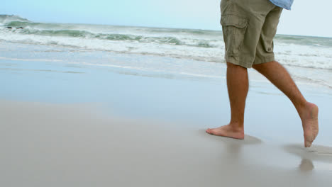 Low-section-of-barefoot-man-walking-on-the-beach-4k