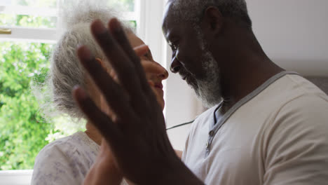 Close-up-of-mixed-race-senior-couple-dancing-together-in-the-kitchen-at-home