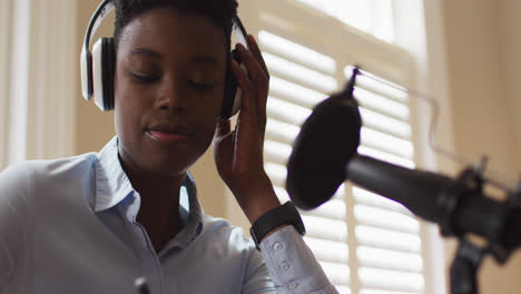 Afroamerikanerin-Mit-Kopfhörern-Macht-Sich-Notizen,-Während-Sie-Auf-Den-Laptop-Schaut