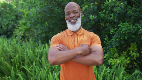 Retrato-De-Un-Anciano-Afroamericano-Sonriendo-Y-Cruzando-Los-Brazos-En-El-Jardín