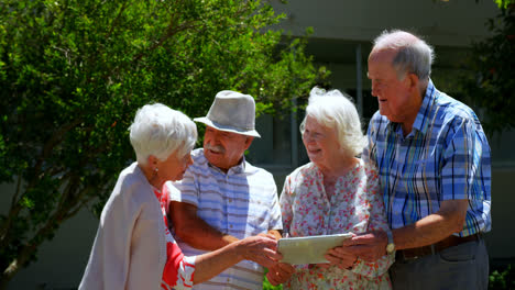 Group-of-Caucasian-senior-couples-discussing-over-digital-tablet-in-the-garden-of-nursing-home-4k
