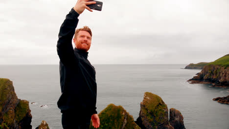 Man-taking-selfie-from-mobile-phone-on-cliff-4k