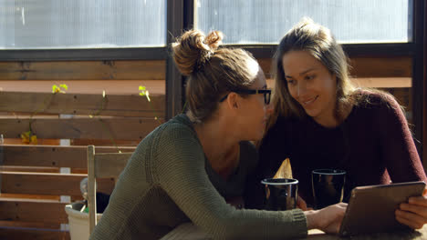 Lesbian-couple-interacting-with-each-other-at-cafe-4k