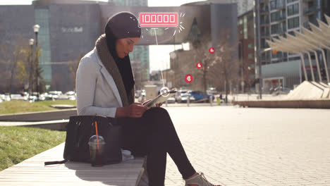 Animation-of-mixed-race-woman-wearing-hijab-in-street-using-tablet-computer-with-floating-heart-symb
