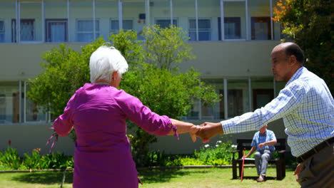 Seitenansicht-Eines-Aktiven-Seniorenpaares-Gemischter-Herkunft,-Das-Zusammen-Im-Garten-Eines-Pflegeheims-Tanzt,-4k