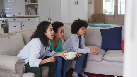 Mischlinge-Lesbisches-Paar-Und-Tochter-Vor-Dem-Fernseher-Essen-Popcorn