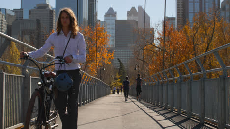 Front-view-of-young-Caucasian-man-walking-with-bicycle-on-the-bridge-4k