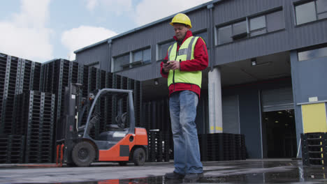 Warehouse-worker-using-phone-outside-factory