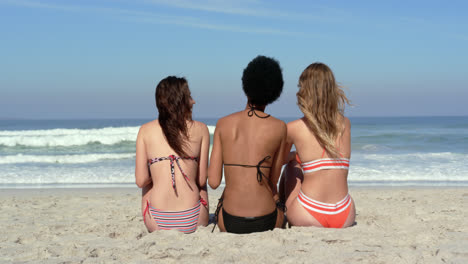 Young-female-friends-sitting-together-at-beach-4k