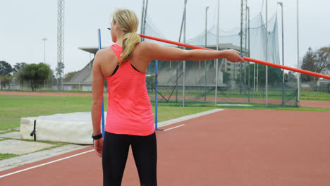 Rear-view-of-Caucasian-female-athlete-getting-ready-for-javelin-throw-at-sports-venue-4k