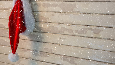 Fallender-Schnee-Mit-Weihnachtsmütze-Auf-Holz