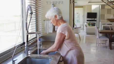 Senior-caucasian-woman-washing-her-hands-in-the-sink-at-home